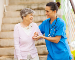 caregiver assisting patient in walking down the stairs